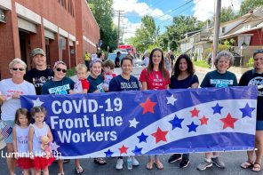 Healthcare workers standing behind banner that says COVID-19 Front Line Workers