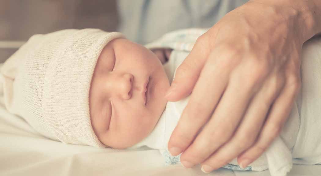 Hand comforting newborn infant